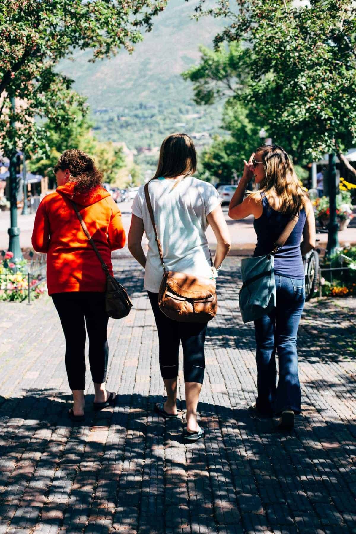 Three women walking on a sidewalk.