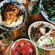 Busy table with plates of food and drinks.