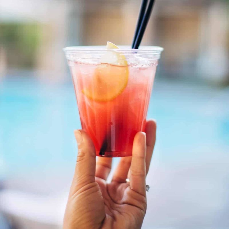 Hand holding a cocktail by the pool.